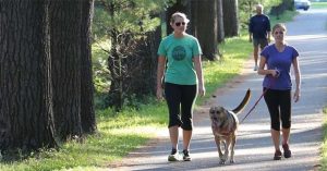 2 women walking dog in a park